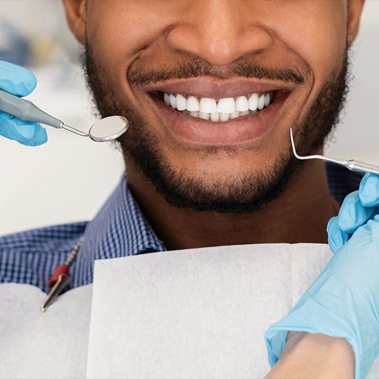 Man smiling with gum disease treatment tools by his mouth