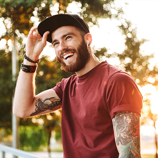 Man with tattoos smiling after root canal therapy