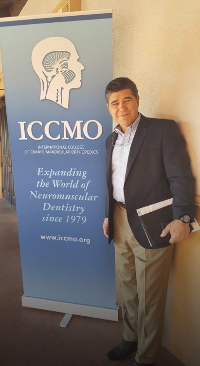 Covington dentist standing next to sign at event for the International College of Cranio Mandibular Orthopedics