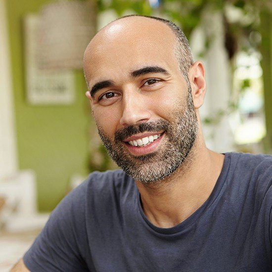 Man in grey shirt with beard smiling after CEREC same day dental crown restoration