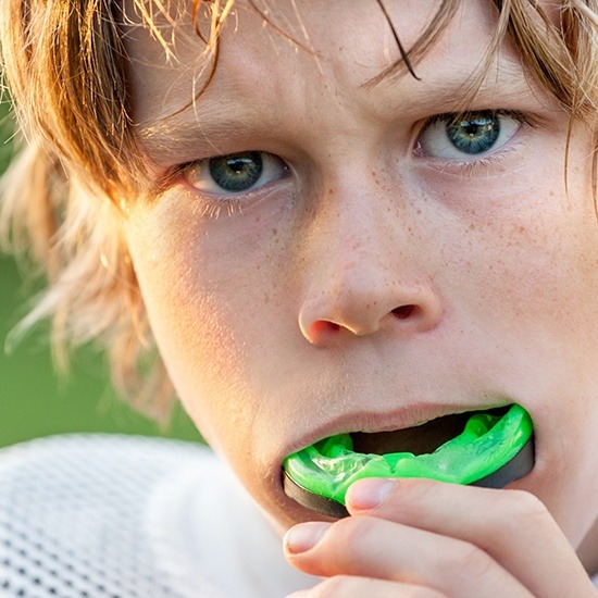 Boy placing green athletic mouthguard