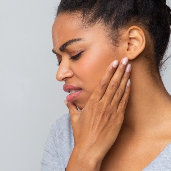 Woman holding jaw in pain before T M J therapy