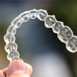 Patient holding up Invisalign aligner outside