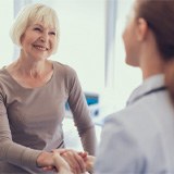 Senior woman smiling while shaking dentist's hand