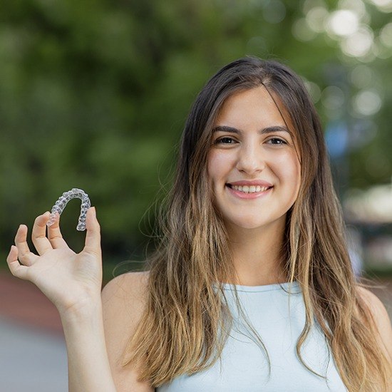 Woman holding Invisalign clear aligner tray