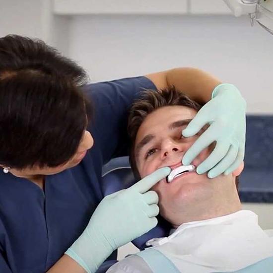 Dental team member fitting sleep apnea oral appliance for male patient