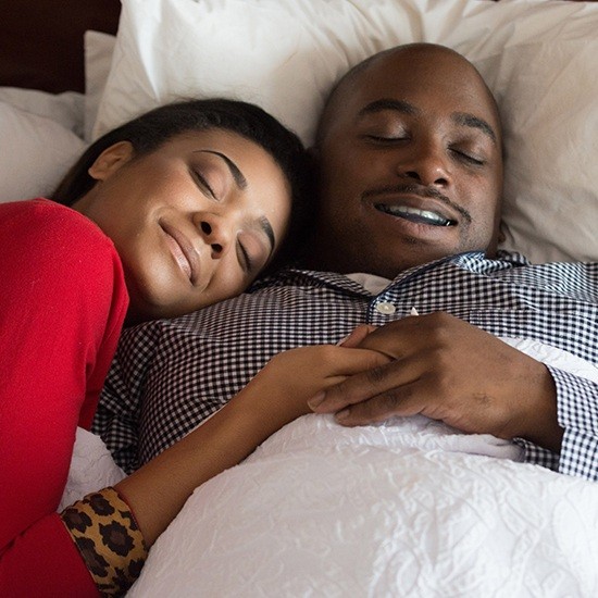 Man and woman peacefully sleeping thanks to sleep apnea treatment