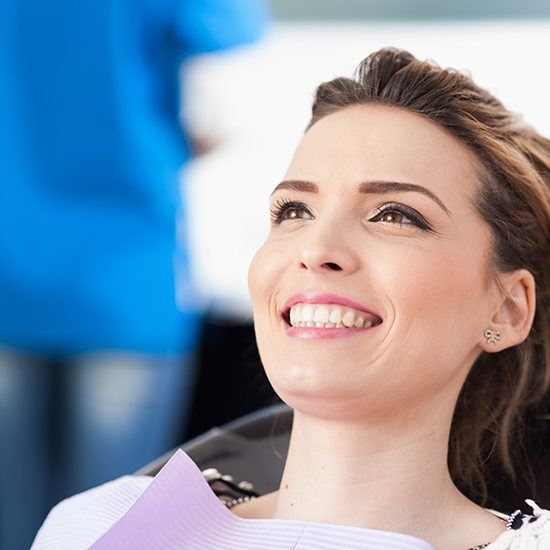 Woman laying back in exam chair for dental checkup and teeth cleaning