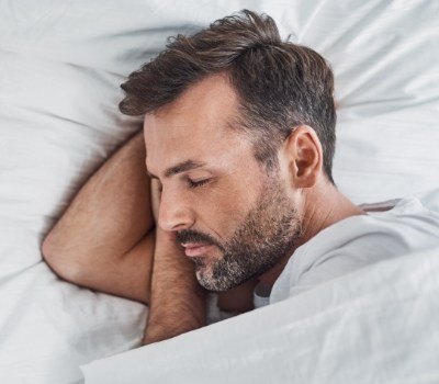 Man laying in bed asleep thanks to sleep apnea treatment