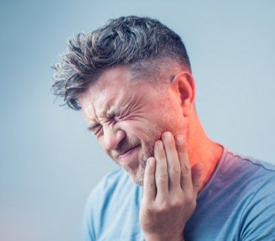Man wincing in pain before emergency dentistry