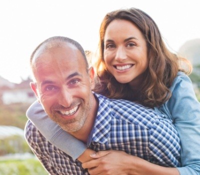 Husband giving wife piggyback ride after gum disease treatment