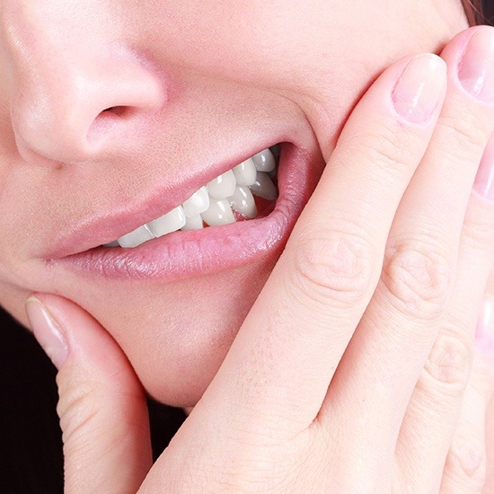 Close shot of woman wincing in pain before tooth extractions