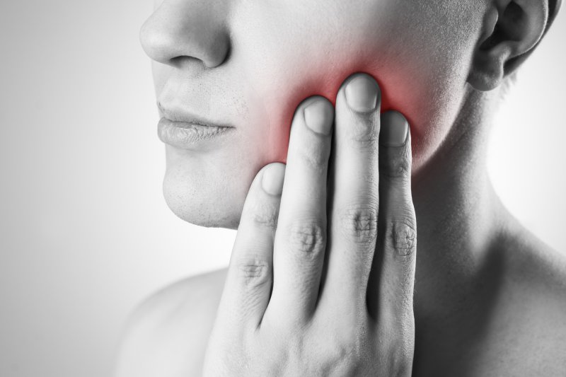 Woman holding her cheek due to TMJ pain